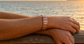 Man's crossed forearms at sunset wearing a copper magnetic bracelet on one wrist only